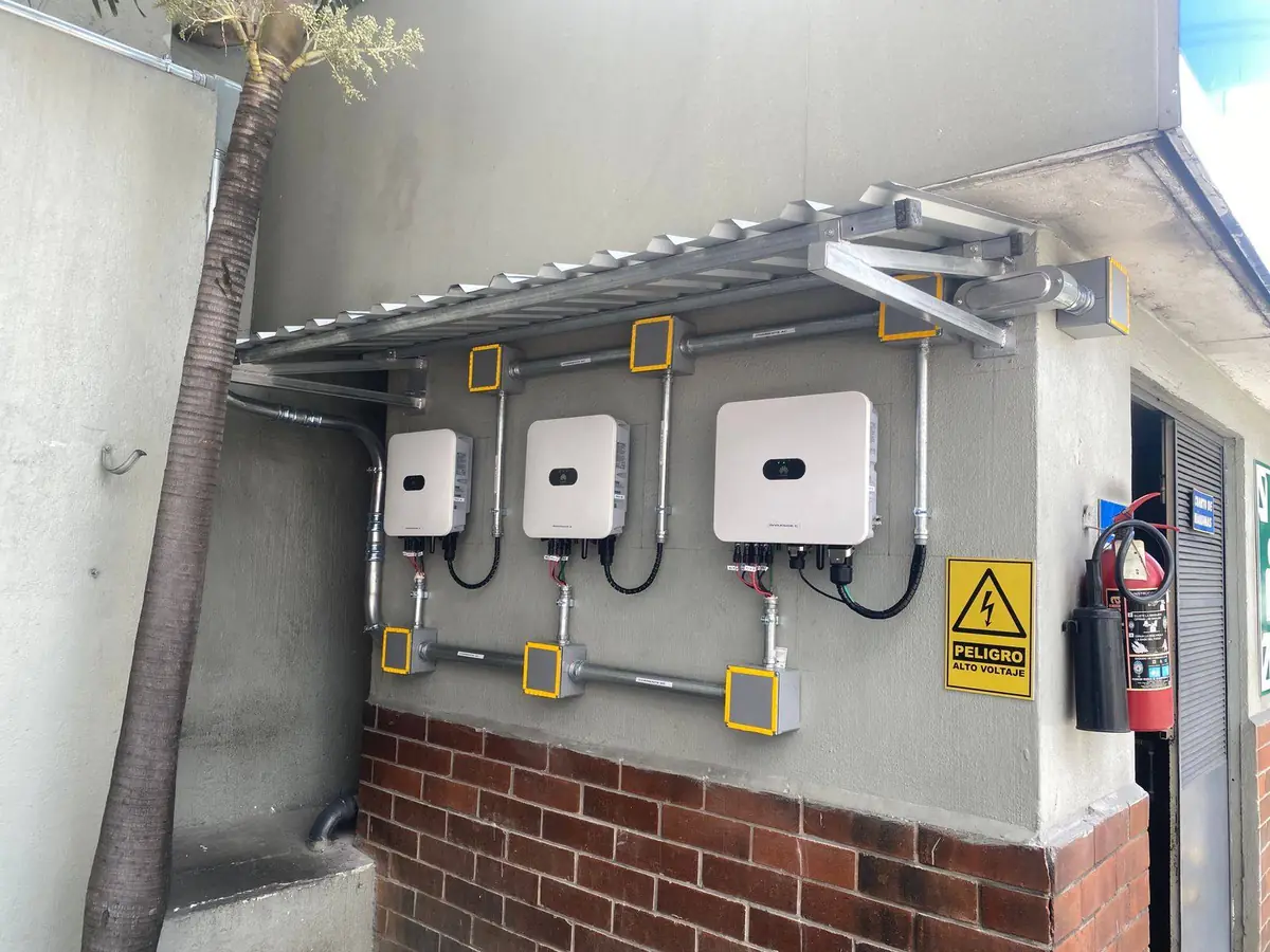 Inversores instalados en un muro exterior con tablero y señalización de seguridad