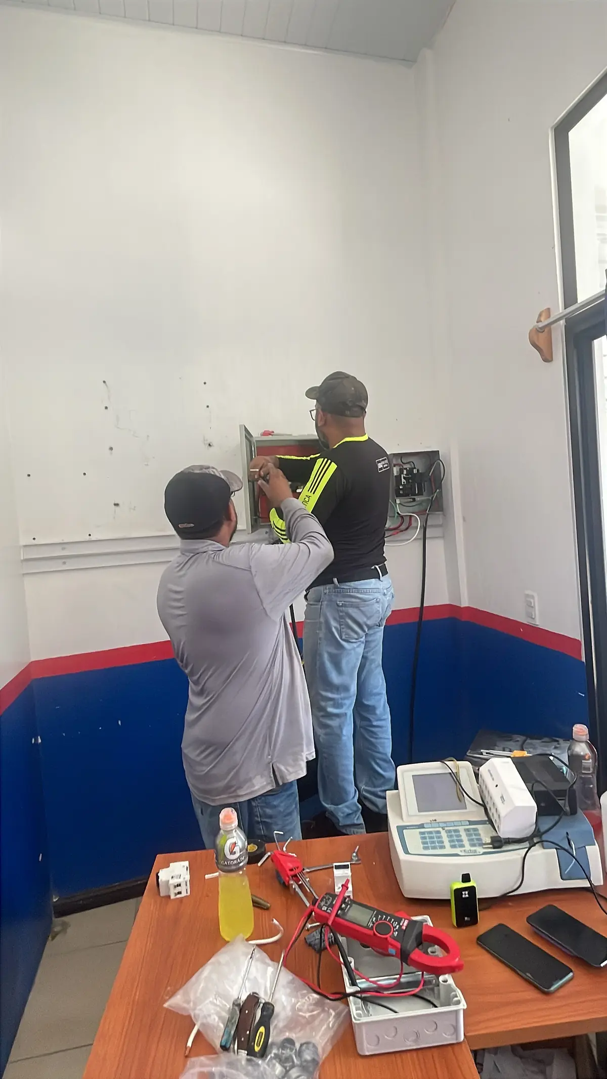 Dos técnicos trabajando en las conexiones de un tablero eléctrico